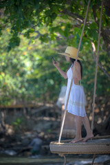 Obraz premium Woman tourist in dress play around on the wooden swing at the edge of the sea beach, enjoy moment of the woman in summer trip