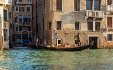 Gondolier steering a gondola through Venice canal © Alberto Retouch