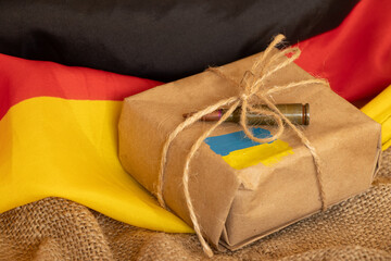 Gift box with Ukrainian flag and bullet against the background of the German flag, humanitarian and...