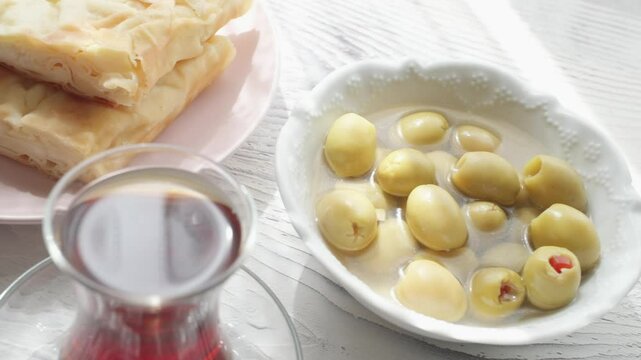 Local Turkish breakfast table Turkish tea, su boregi, green olives and simit bagel	