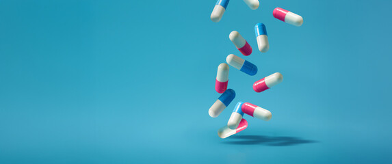 Falling pills on a blue background. Antibiotics A blue and pink pill is falling On a Isolated Blue...