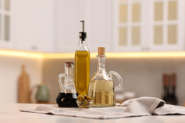 Bottles of salad dressings and olives on white table in kitchen