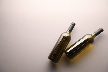 Bottles of wine on light grey background, flat lay. Space for text