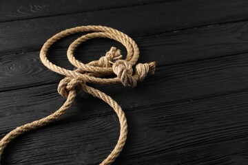 Obraz premium Lasso made of cotton rope on black wooden background, closeup. Space for text