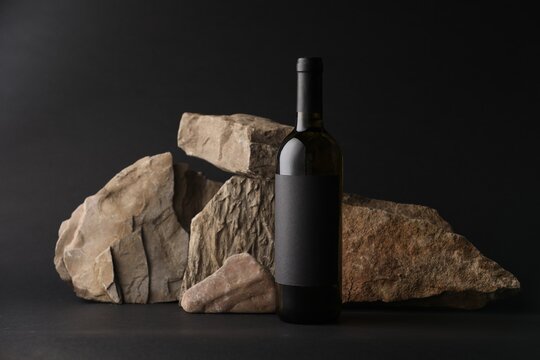 Bottle of wine and rocks on black background