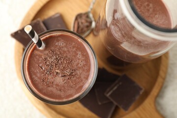Tasty chocolate milk with shavings and pieces on white table, top view
