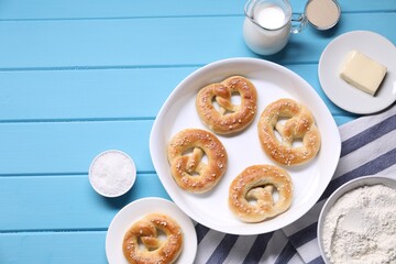 Tasty pretzels and ingredients on light blue wooden table, flat lay. Space for text