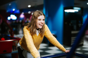 Young woman enjoys fun arcade game in lively entertainment center