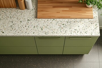 Modern kitchen countertop with sage green cabinets, wood cutting board, and speckled surface