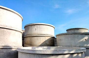 Group of concrete well rings with different diameters stacked on the ground outside of hardware...