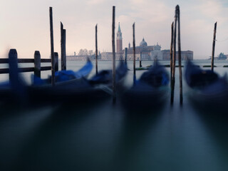 Long exposure photo of Gondolas moored near San Marco square at sunrise with a view at San Giorgio...