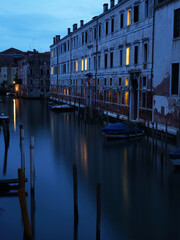 Long exposure evening photo of canal in Venice with buildings and moored boats. Venice, Italy.