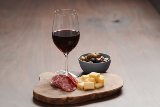 olives, salami and vintage cheese with glass of red wine on walnut table
