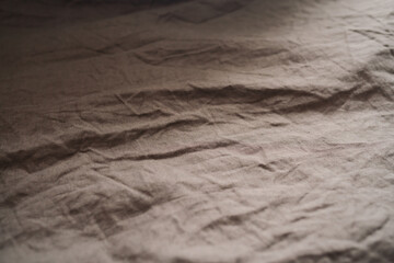 brown crumpled linen bed cover with sunlight from window