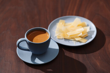 Fresh espresso in blue cup with cheese flakes on walnut table