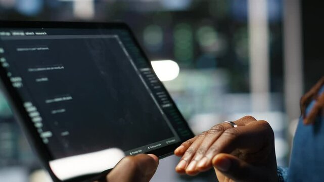 Close up of server room programmer checking coding on tablet enhancing operational efficiency and reducing downtime. Developer verifying programming language script used to update gear, camera B