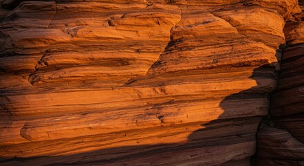Striated sandstone rock formation exhibiting geological layers at sunset