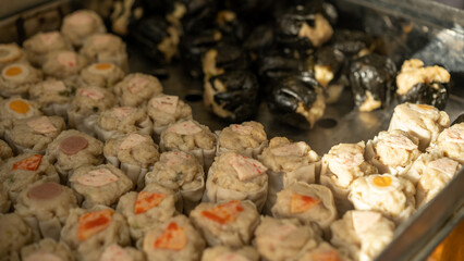 Assorted steamed dim sum freshly prepared in a metal tray, showcasing traditional Asian street food with savory fillings.