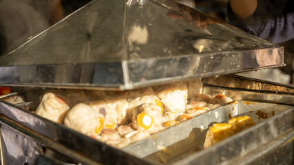 Freshly steamed dim sum inside a hot metal steamer, traditional Asian street food snack served warm, soft texture, delicious homemade recipe, authentic culinary preparation at local food stall.
