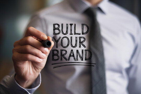 Close-up of hand writing Build Your Brand on a transparent surface, showcasing business concept of brand development and growth, ideal for marketing or advertising campaigns