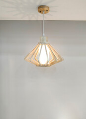 Modern hanging lamp and geometric wooden cage with illuminated lighting on white ceiling and gray wall in living room, front view and vertical frame