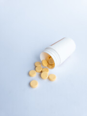Vitamin B tablets and a white supplement bottle on a white background