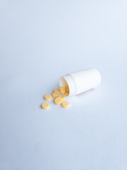 Vitamin B tablets and a white supplement bottle on a white background