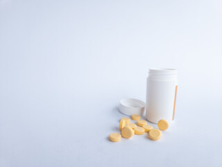 Vitamin B tablets and a white supplement bottle on a white background