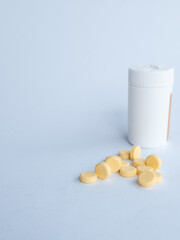 Vitamin B tablets and a white supplement bottle on a white background