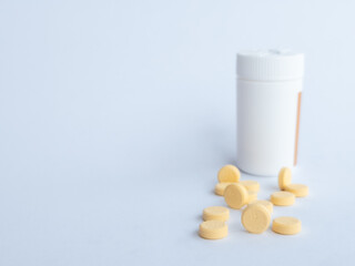 Vitamin B tablets and a white supplement bottle on a white background