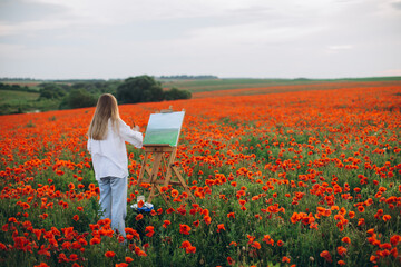 Woman artist painting in poppy field en plein air