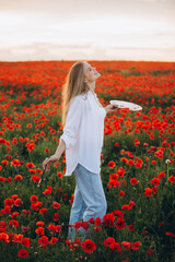 Female artist painting in poppy field at sunset