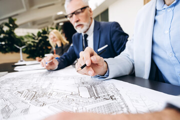 Architects and engineers reviewing blueprint in modern office, selective focus ,close up