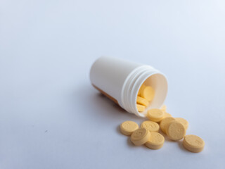 Vitamin B tablets and a white supplement bottle on a white background