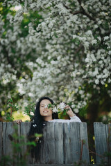 A girl with long dark hair among a blooming apple tree