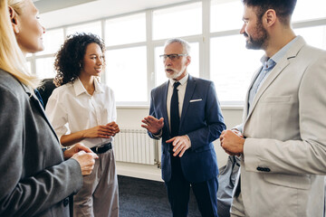 Senior businessman leading meeting with diverse team in modern office