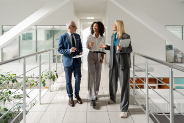 Business people walking and talking in modern office hallway