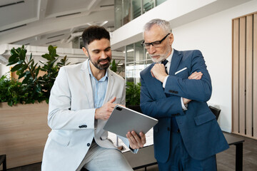 Businessmen discussing work using digital tablet in modern office