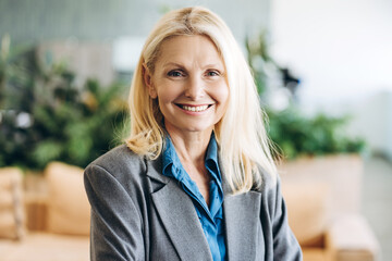 Smiling middle aged businesswoman wearing suit in office: successful career and empowerment