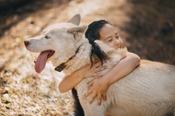 A girl hugs her dog, smiling