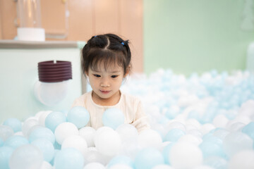 Joyful girl laughing in ball pit at indoor playground