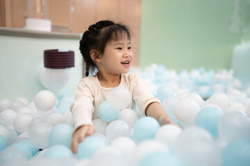 Joyful girl laughing in ball pit at indoor playground