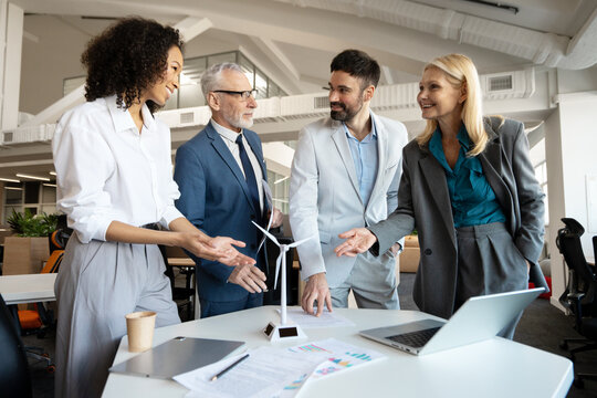 Business people discussing green energy project with wind turbine and solar panel models