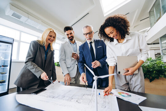 Engineers working on blueprint for wind turbine project in office