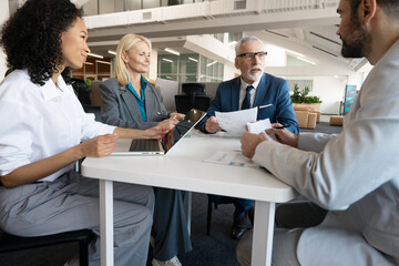 Obraz premium Group of diverse multinational businesspeople working together at office desk discussing report