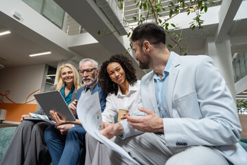 Business people discussing market data in modern office lobby
