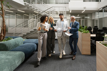 Group of diverse multinational business people walking and talking in modern office lobby