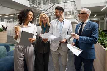 Group of diverse multinational business people walking and talking in modern office lobby