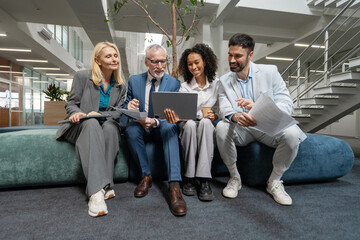 Businesspeople working together on project using laptop in office lobby