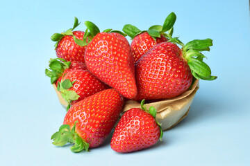 Strawberries in a kraft paper bag, on a light blue background.	
